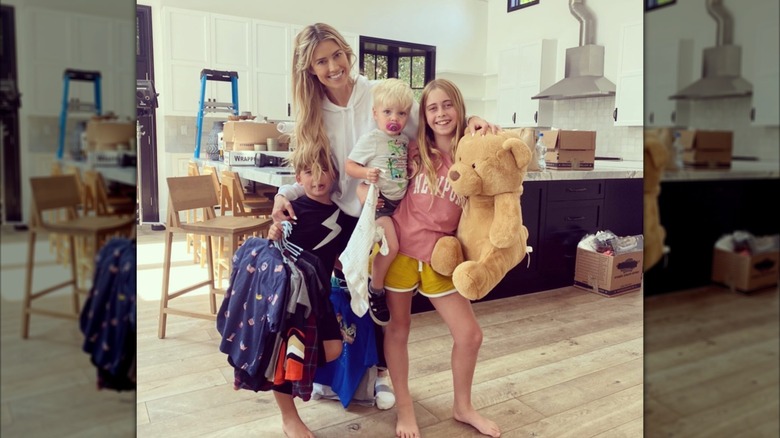 Christina Haack, Taylor, Brayden, and Hudson posing together with a teddy bear in a kitchen with moving boxes.