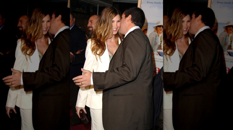Jackie Sandler smiles as Adam Sandler whispers in her ear