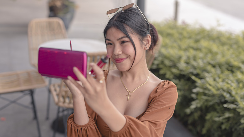 woman applying matte lipstick outside