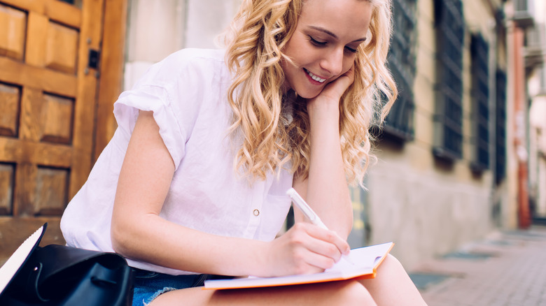 Smiling woman writing in book