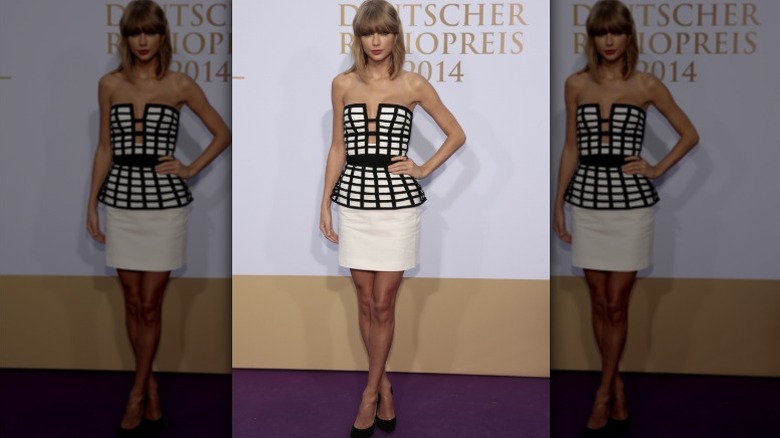 Taylor Swift poses at an event in 2014 wearing a peplum cage style