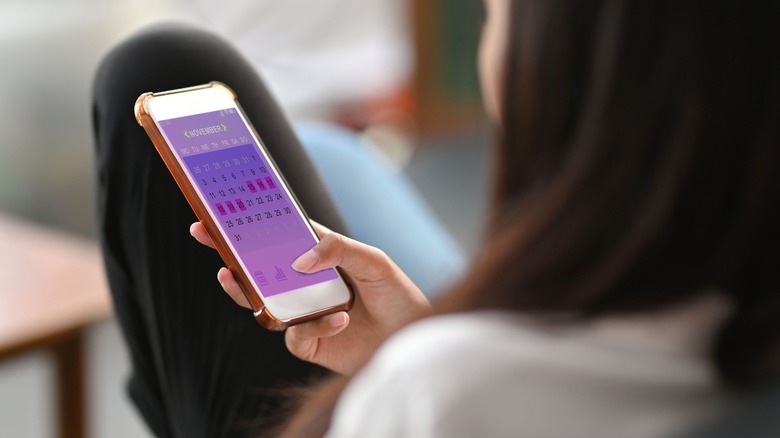 woman holding phone with period tracker