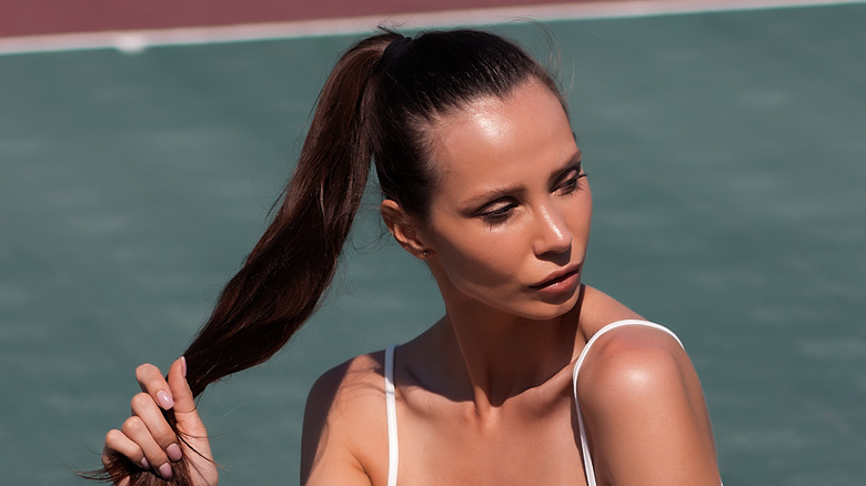 Woman sitting on tennis court ponytail