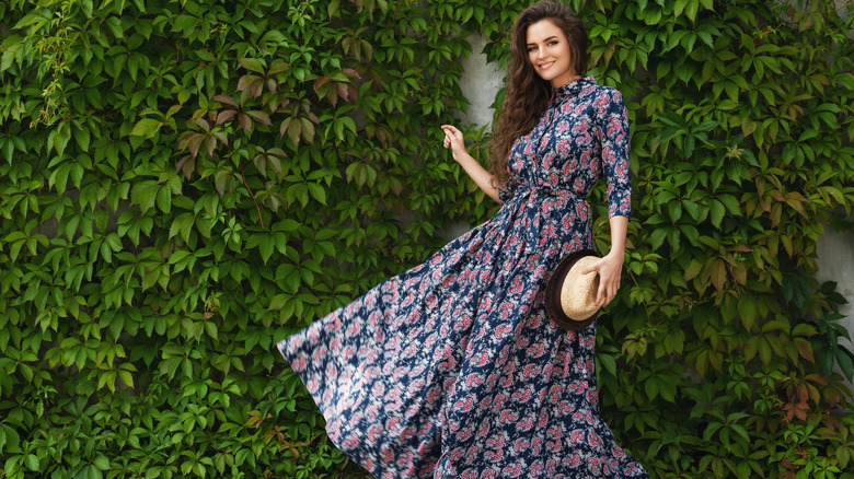 Woman with long tent dress holding hat