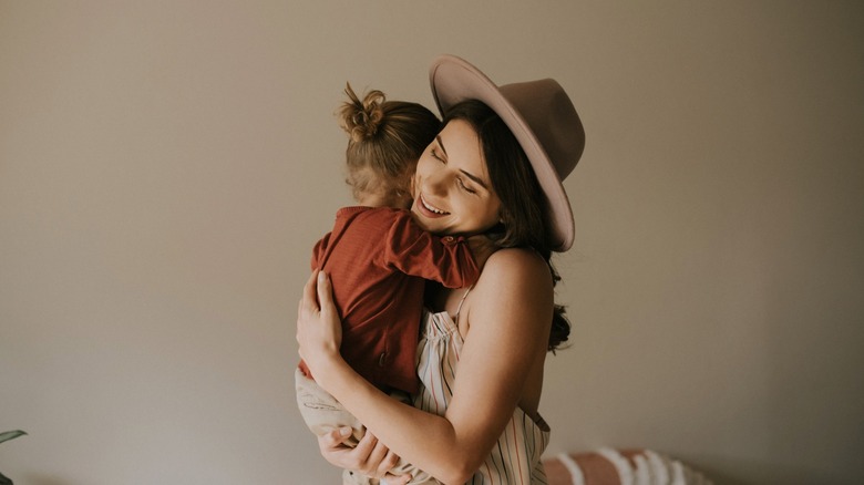 A woman in a rustic, Western-inspired outfit holds her baby.