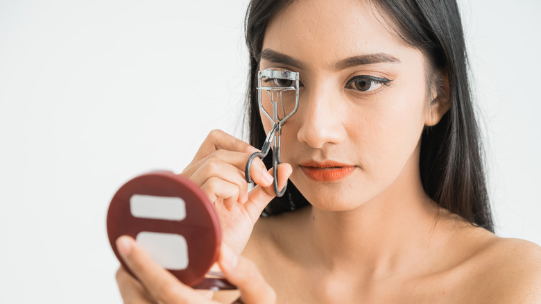 Woman curling her eyelashes