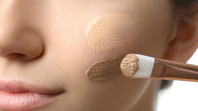 Model applying concealer with a brush