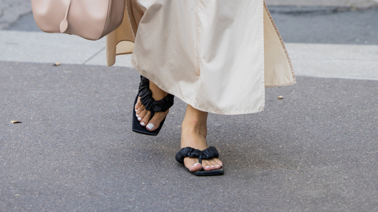A woman wearing detailed flip flop-style sandals