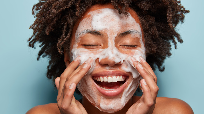 Woman washes face with foaming face wash