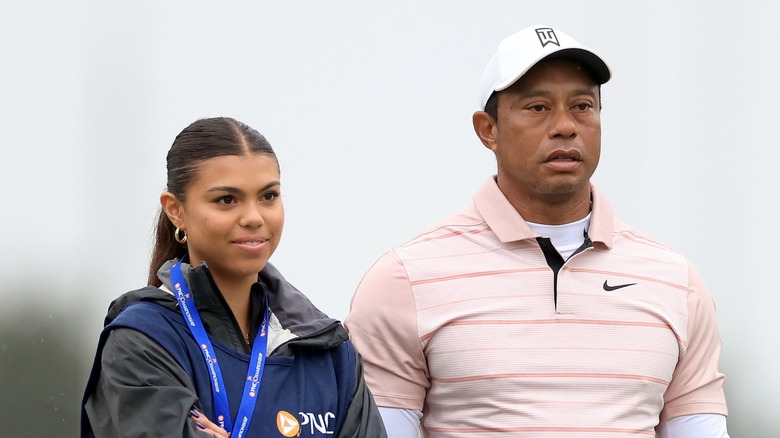 Sam Woods wears her hair in a ponytail with a middle part and small hoop earrings with a gray jacket while attending the PNC Championship in Orlando, Florida in 2023.