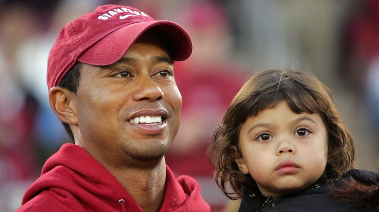 Tiger Woods holds toddler daughter Sam Woods in a black jacket with her brown hair down while attending a Stanford football game in 2009.