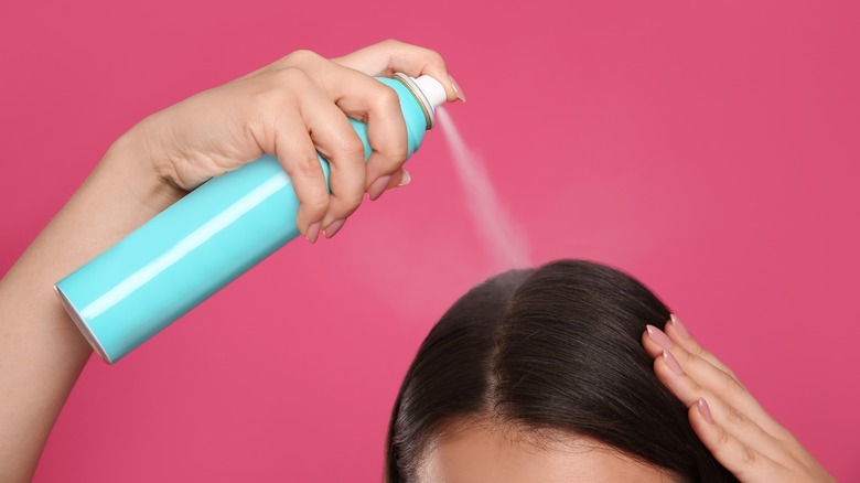 Woman spraying on dry shampoo