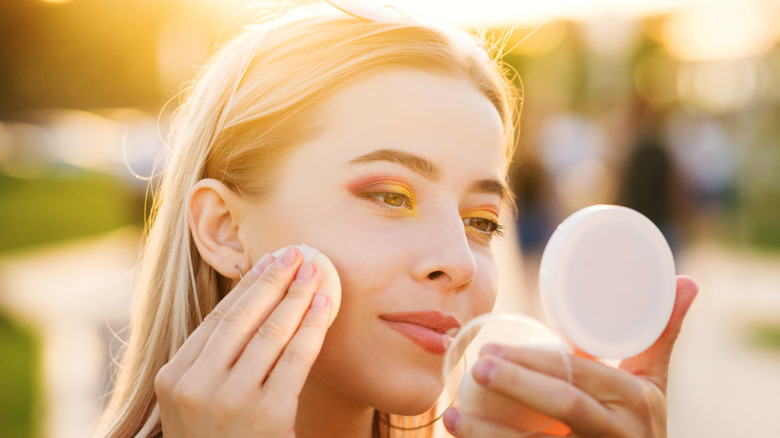 woman finishing makeup in the sun