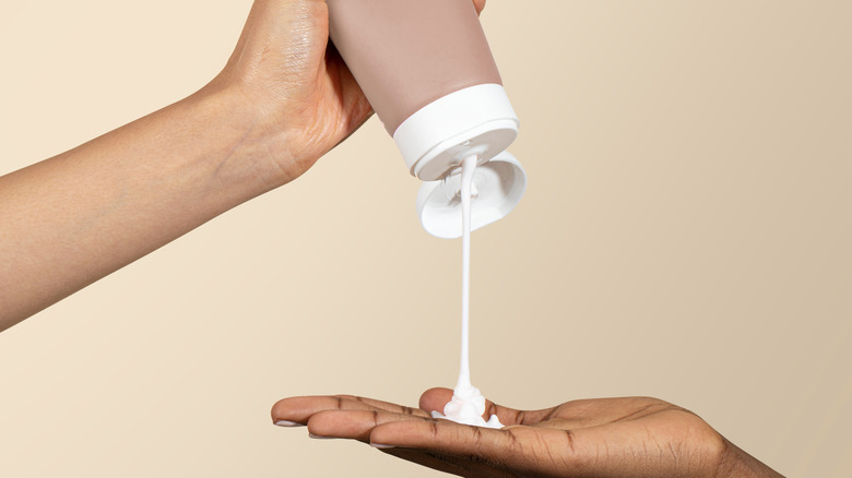person pouring cream on hand