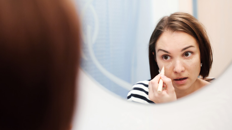 Woman applying under-eye concealer