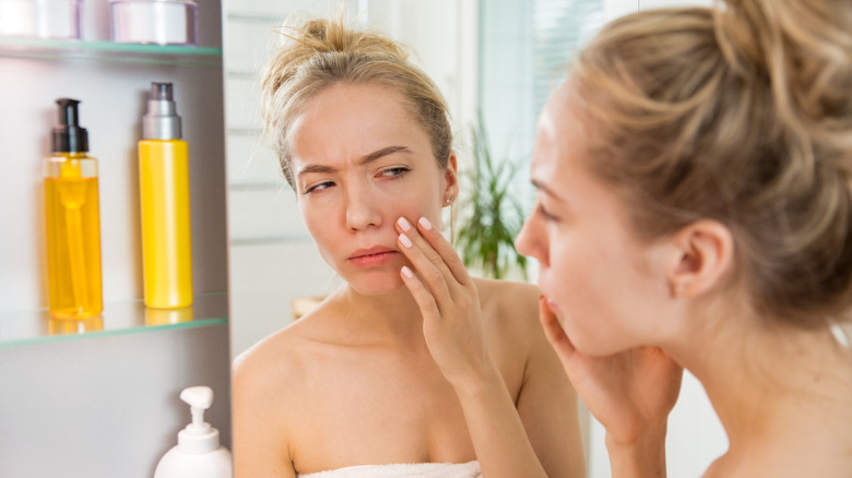 unhappy woman looking at face