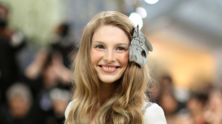 Hunter Schafer smiling at 2026 Met Gala with a gray bow in her hair.