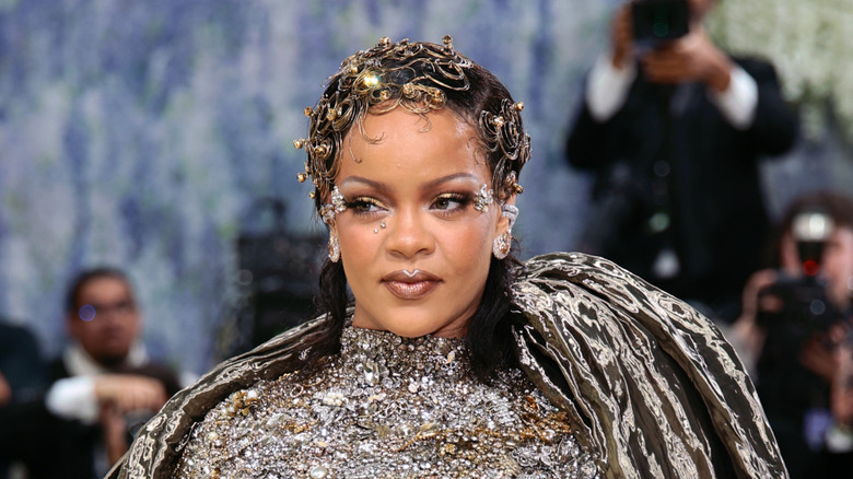 Rihanna at the 2026 Met Gala wearing a metallic outfit with intricate hair.