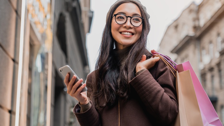 A woman holding her phone while shopping 