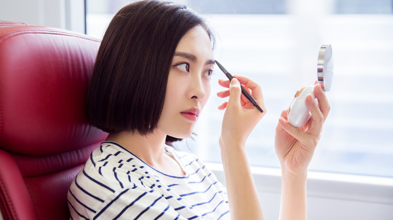 woman applying eyebrow pencil