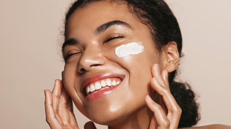 woman smiling with face cream on