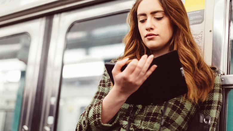 Woman using e-reader on subway