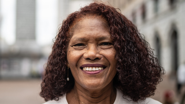 An older woman with a side-parted blunt curly lob