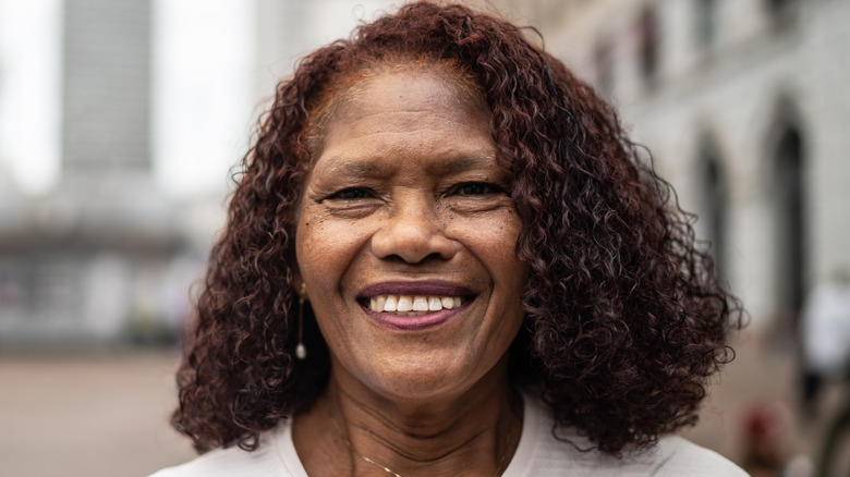 An older woman with a side-parted blunt curly lob