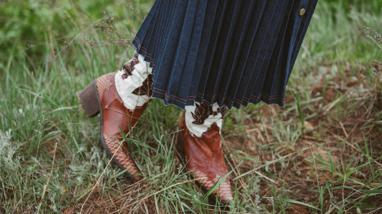 Woman wearing a denim skirt with cowboy boots