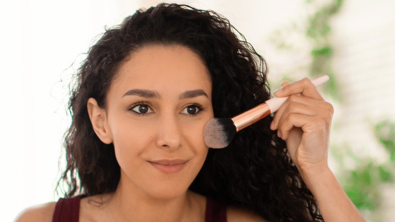 woman applying makeup to face