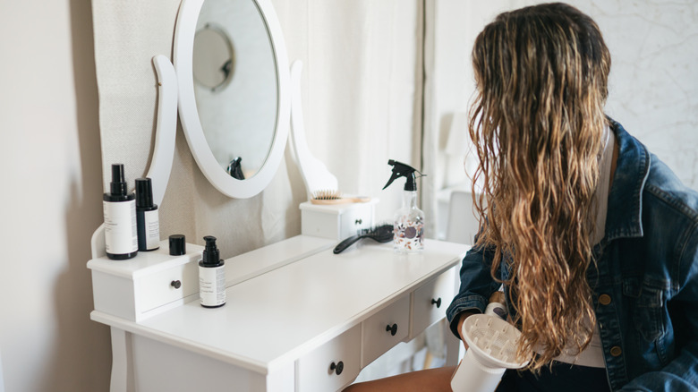 A woman using a hair dryer on her curls