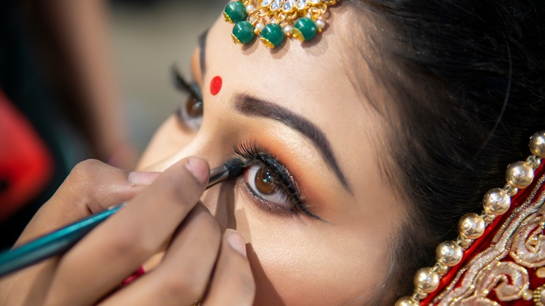 Applying eyeliner to Indian bride