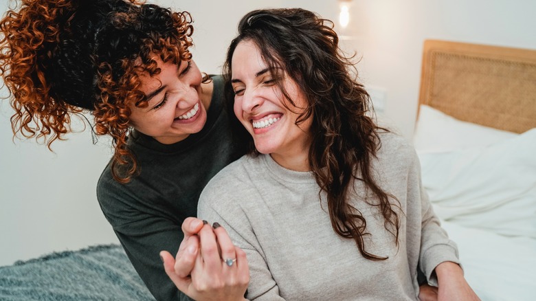 Two women laughing, holding hands