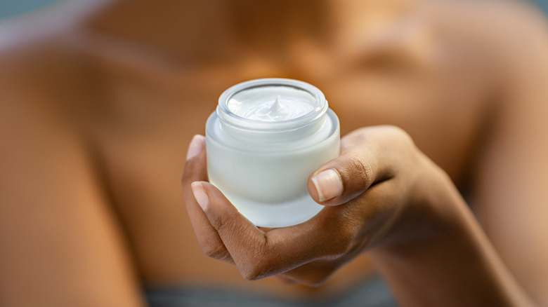 A woman holding a moisturizing cream 