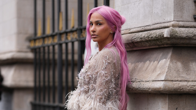 A woman with super-long pink hair poses on the street