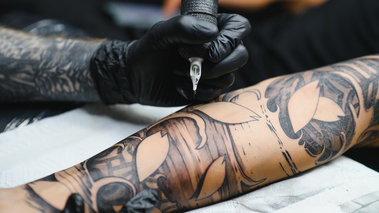 Tattoo artist working on arm tattoo