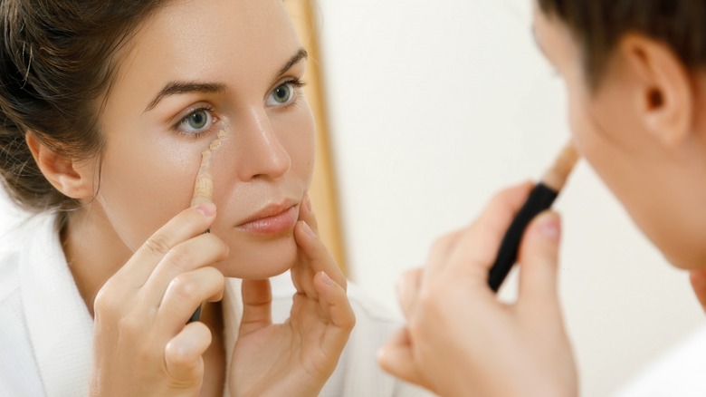 Woman applying concealer under eyes