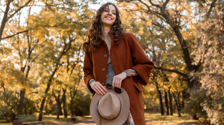 woman in red-orange coat with beige hat in a forest