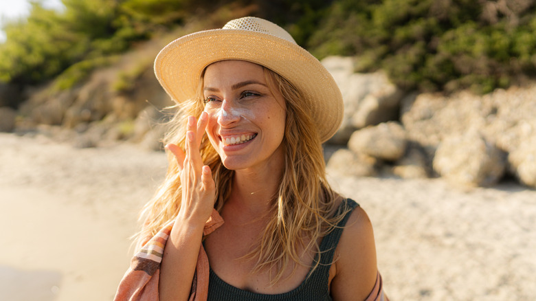Woman smiling putting sunscreen on her face
