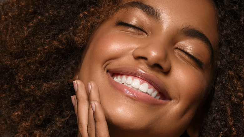 woman smiling holding face