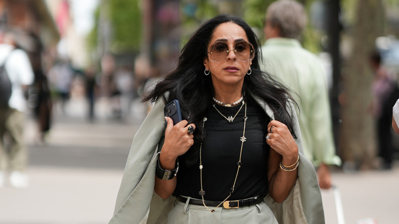 A woman wears a blazer, black tee, and a statement necklace