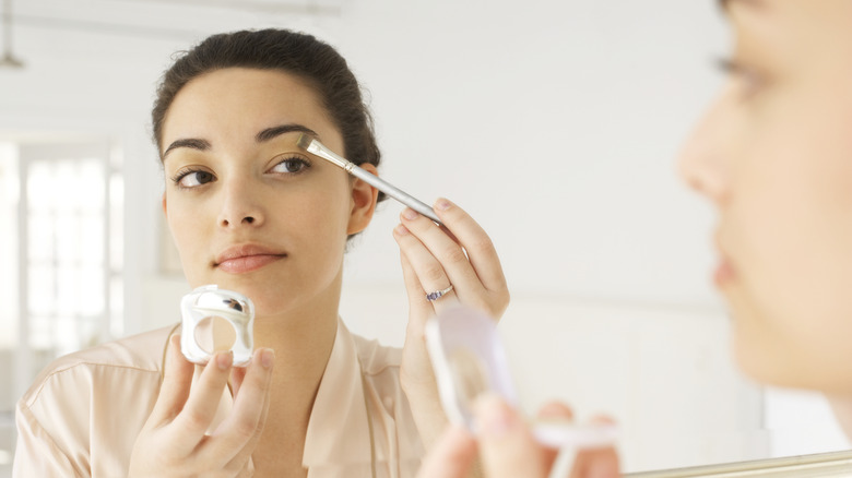 Woman applying concealer under her brow with a brush