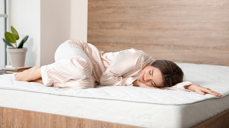 woman laying on mattress in pajamas