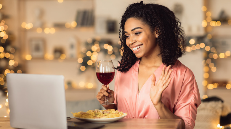 woman holding wine near laptop