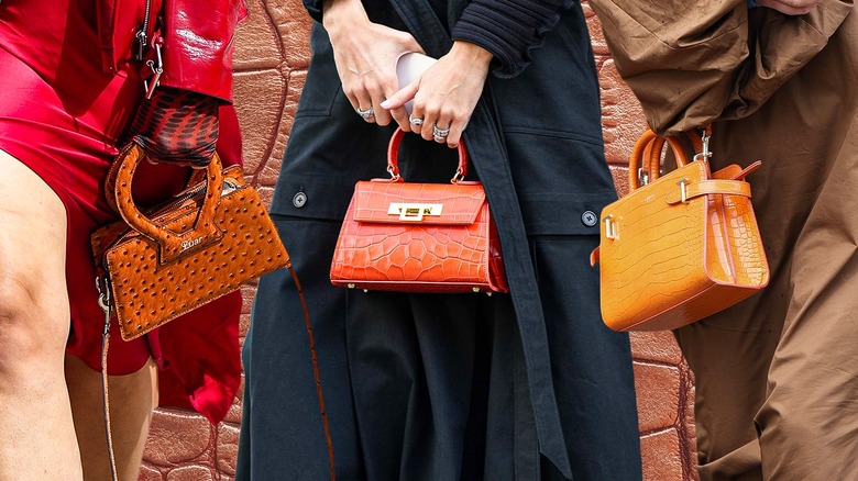 women holding crocodile print handbags