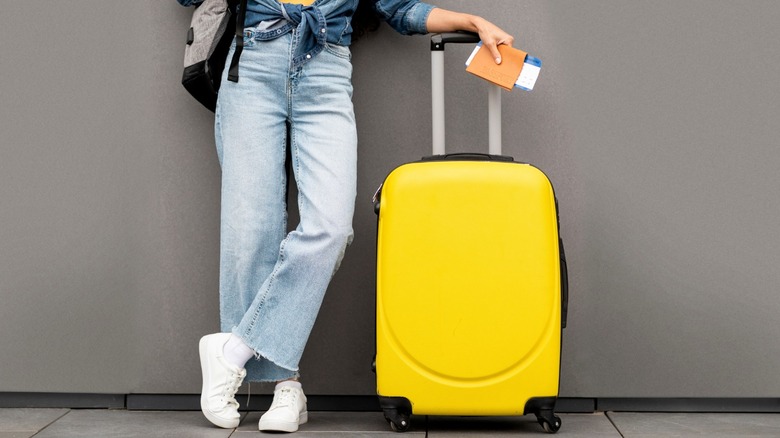 Woman standing with yellow luggage