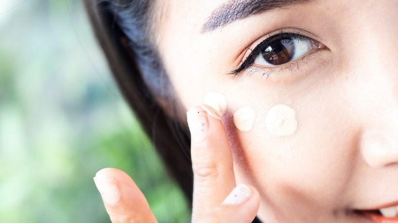 Woman applying concealer under her eye