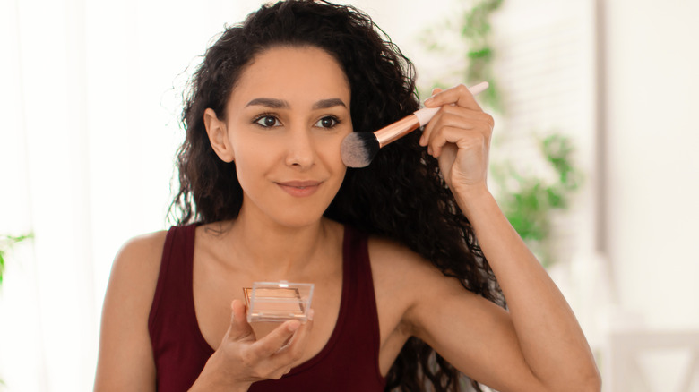 woman applying bronzer to face