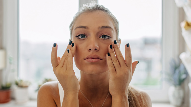 woman holding under eye