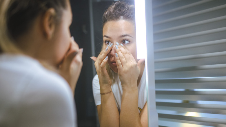 Woman examining eyes in mirror